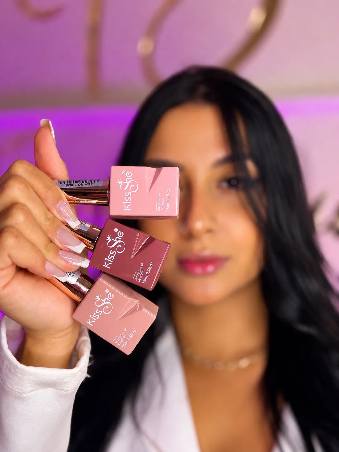 Tainara segurando esmaltes em tons nude e rosados